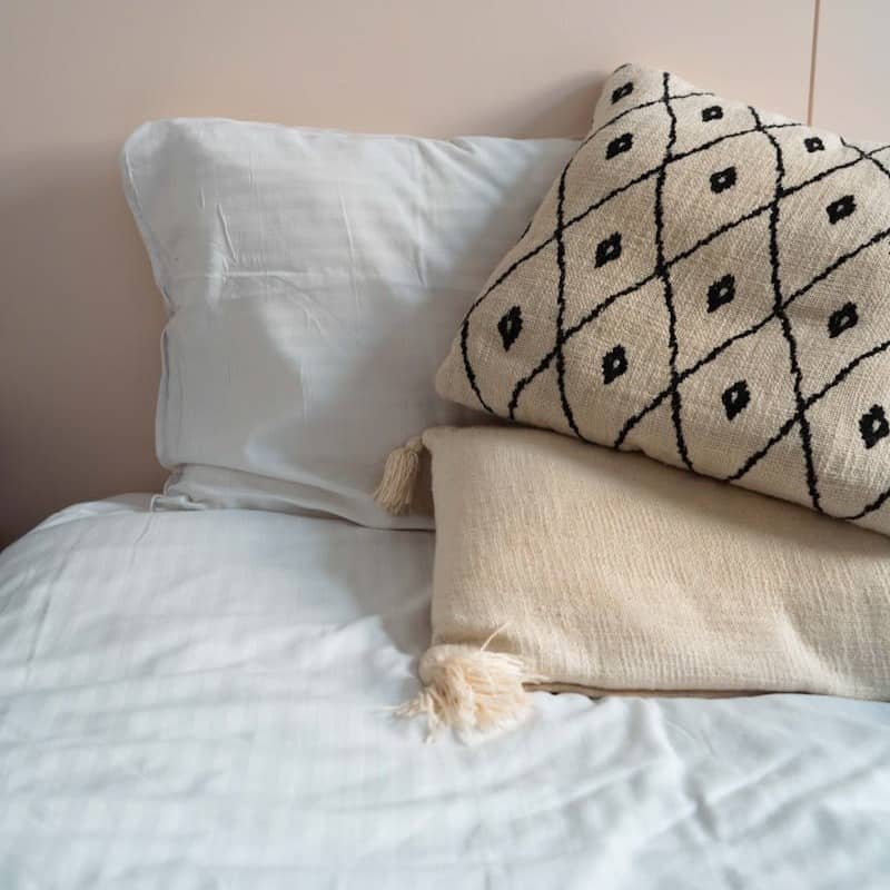 A white bed topped with two pillows and a blanket