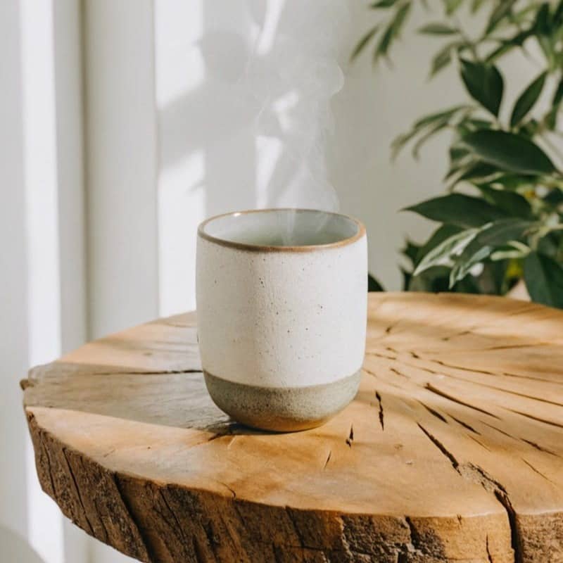 A white cup sitting on top of a wooden table