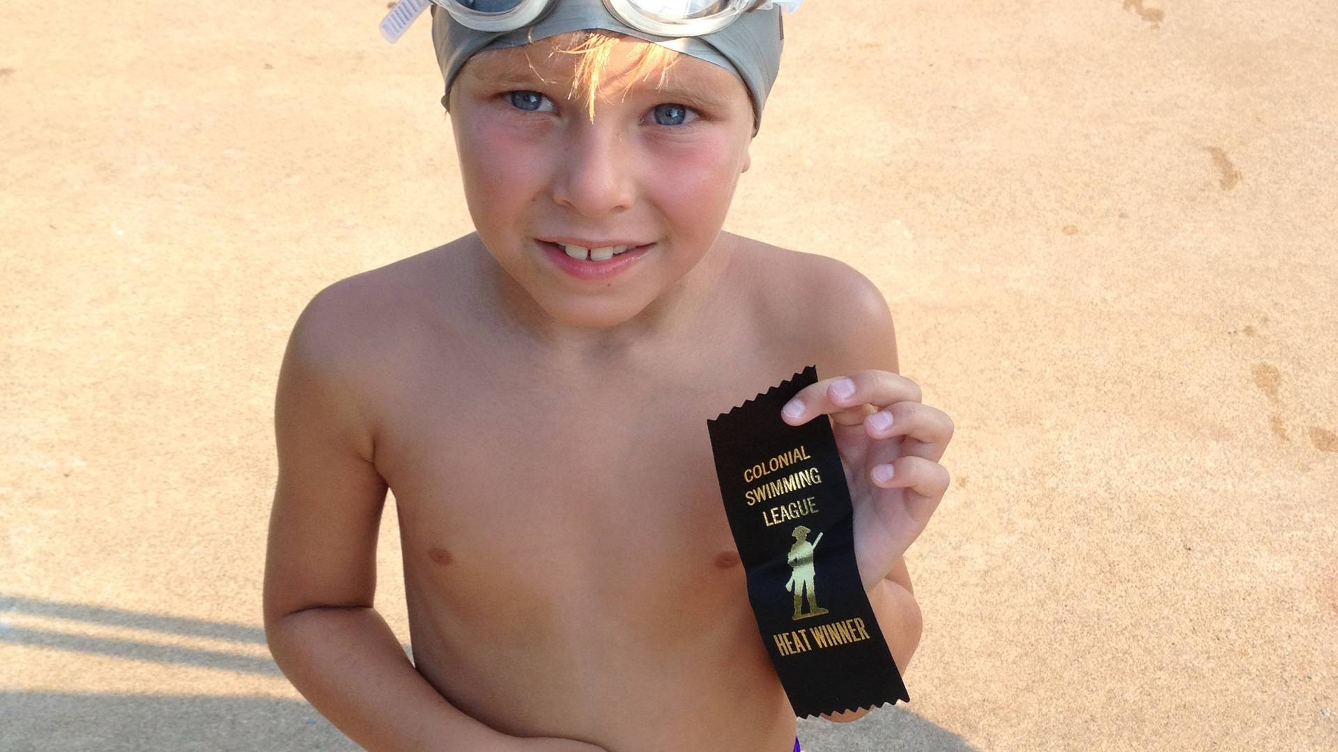 Zack in swim cap and heat winner ribbon