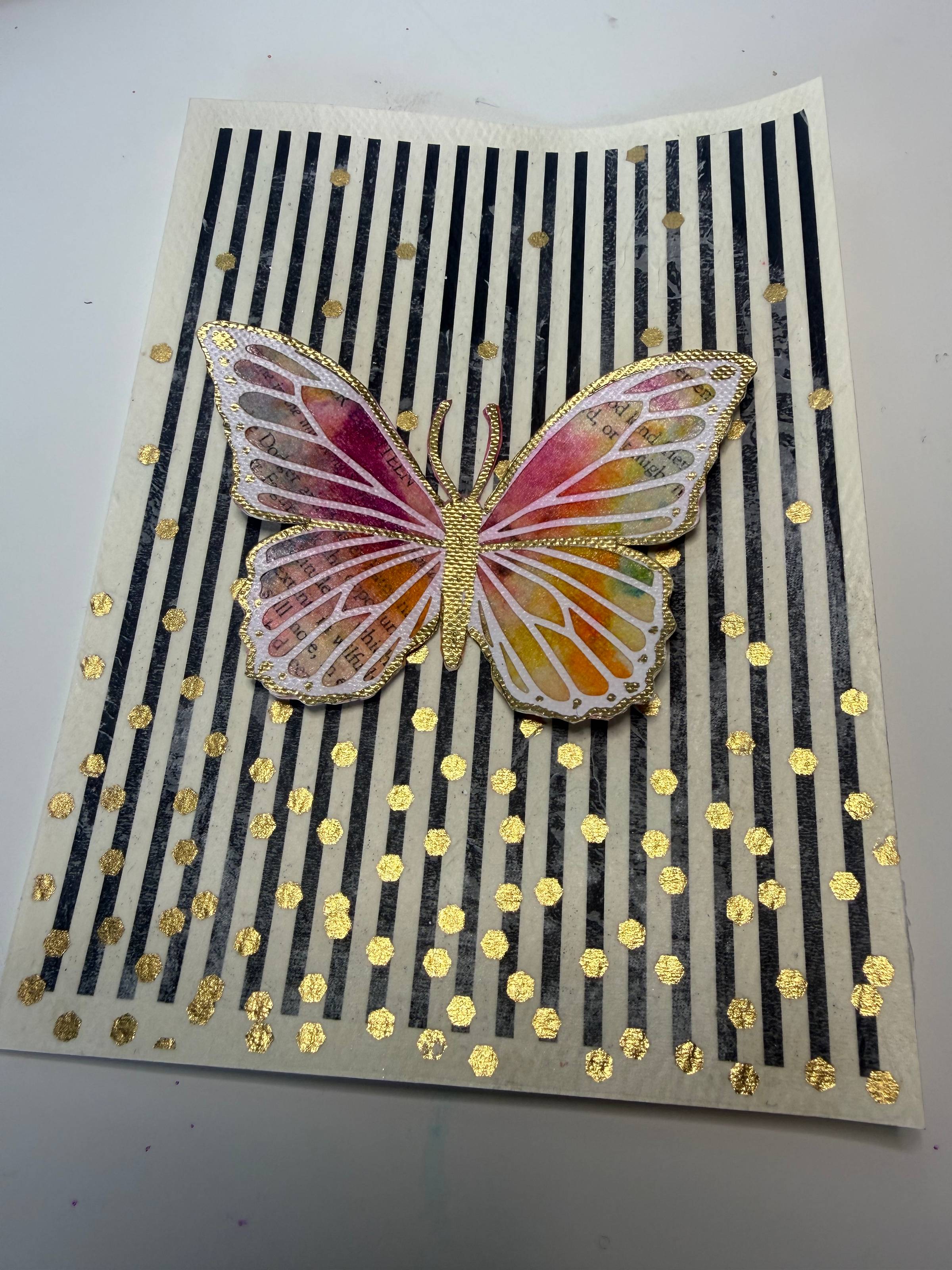 This is a card with black and white stripes for the background and a colorful butterfly in the middle.  There is also gold confetti.