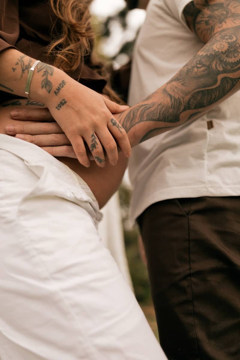 Couple holding pregnant belly with tattoos
