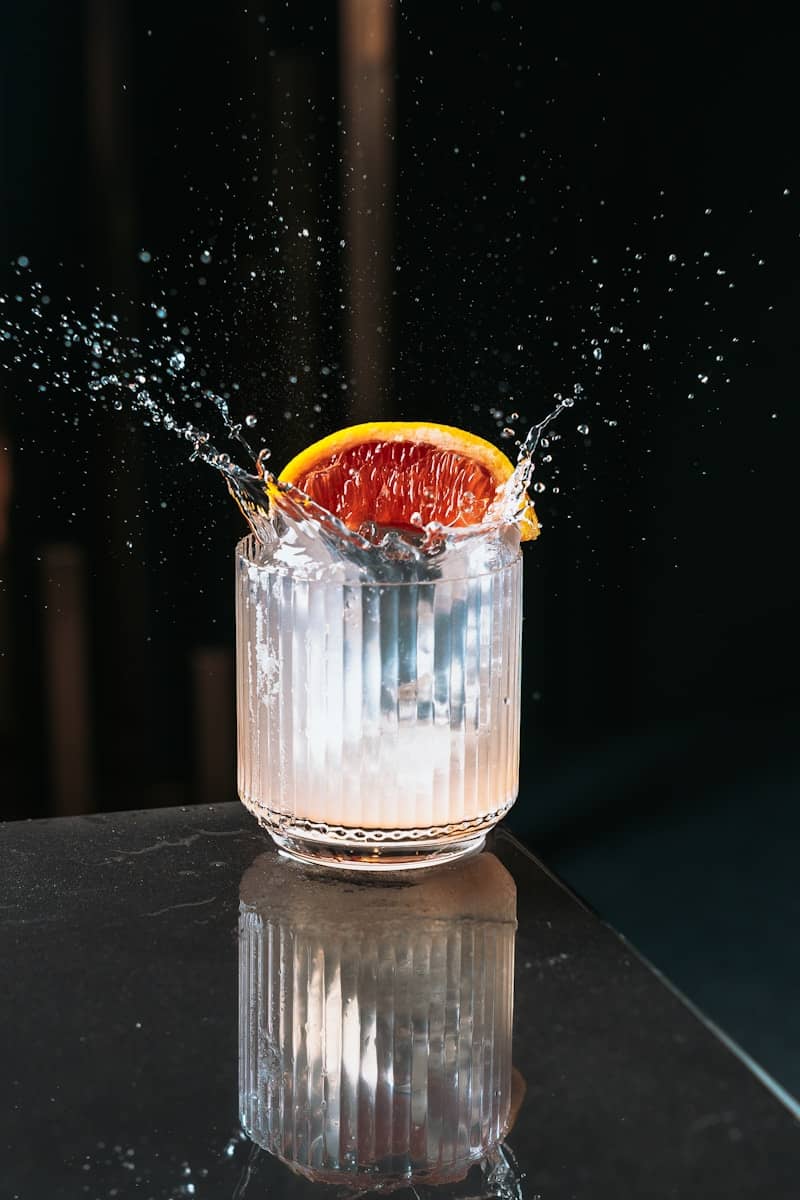 Blood orange slice splashes into a glass.