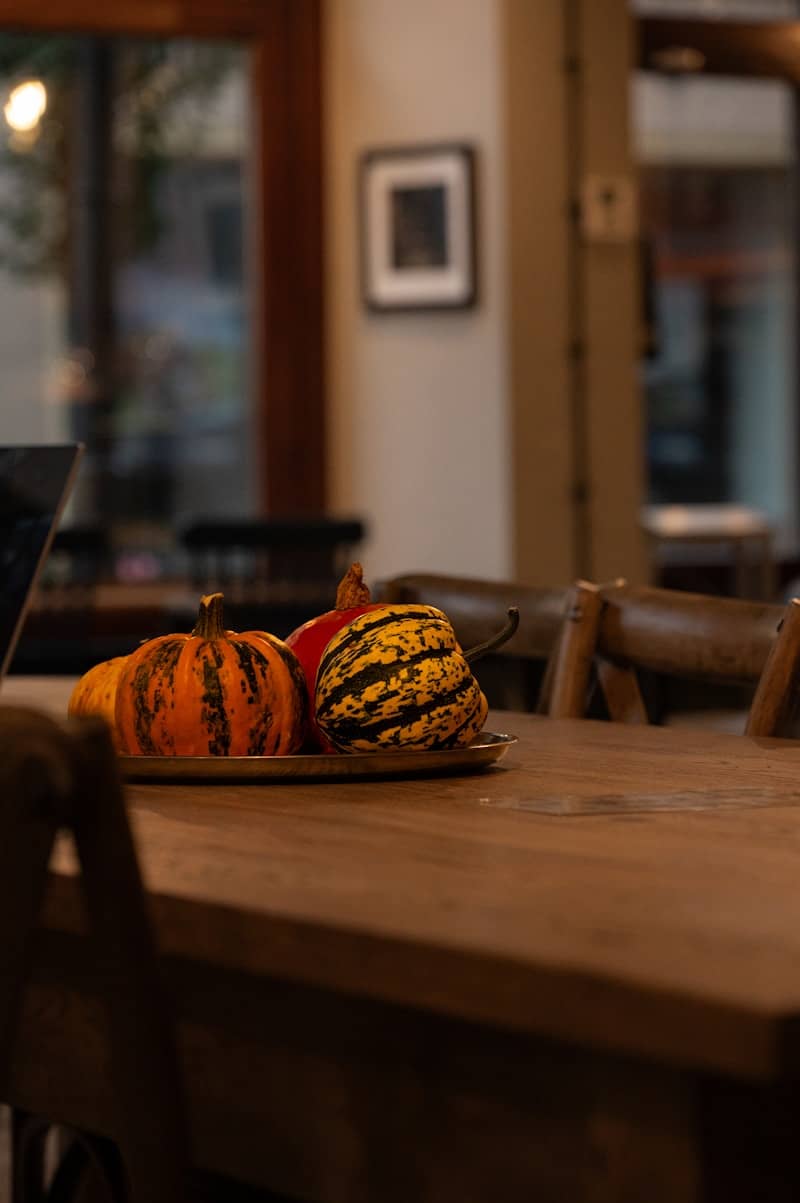 Pumpkins arranged on a wooden table indoors.
