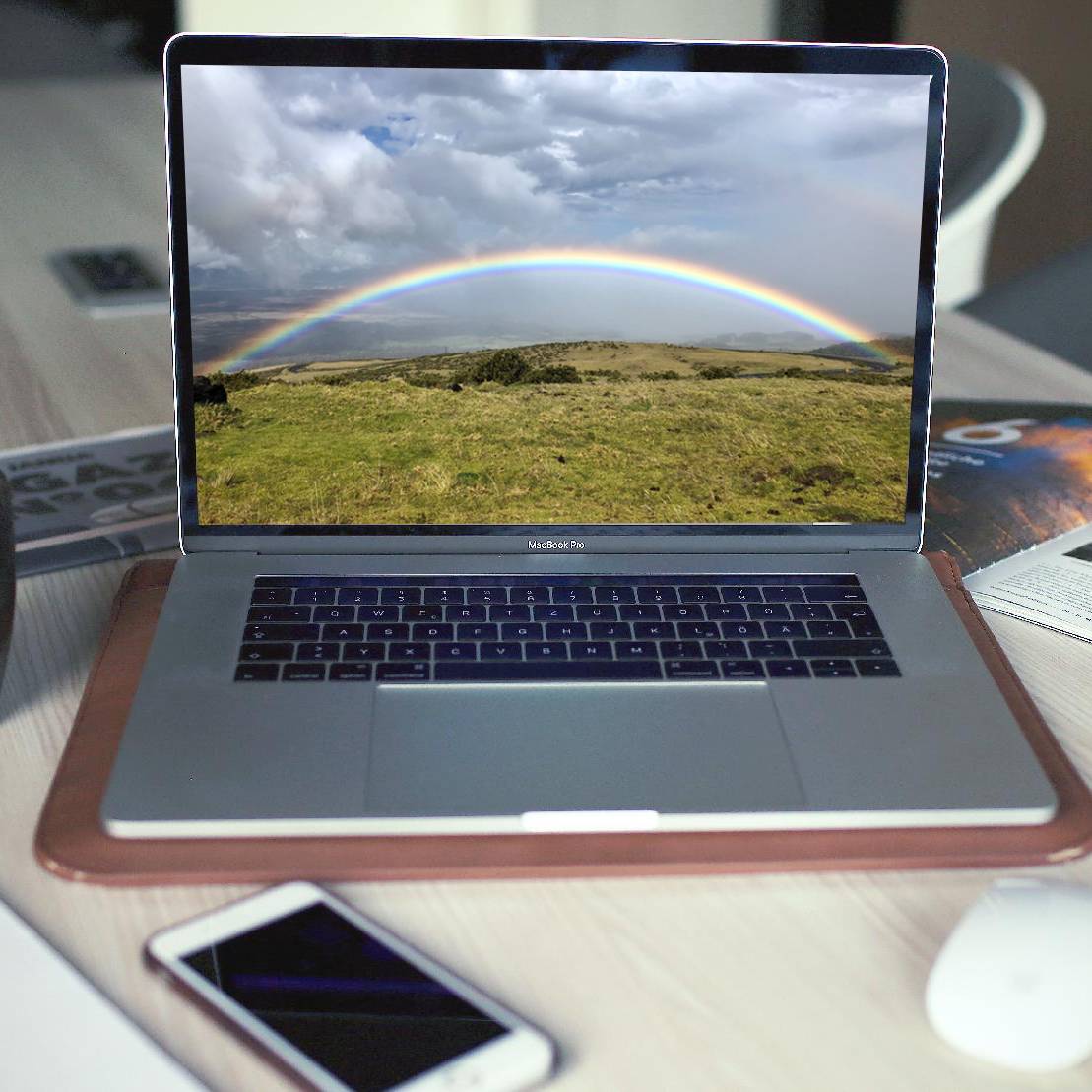 macbook pro beside clear drinking glass on brown wooden table