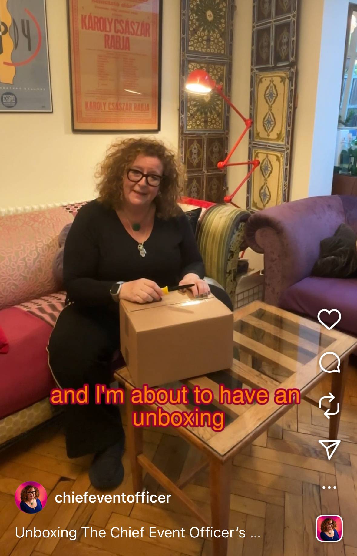 Sasha sitting on her sofa with a box