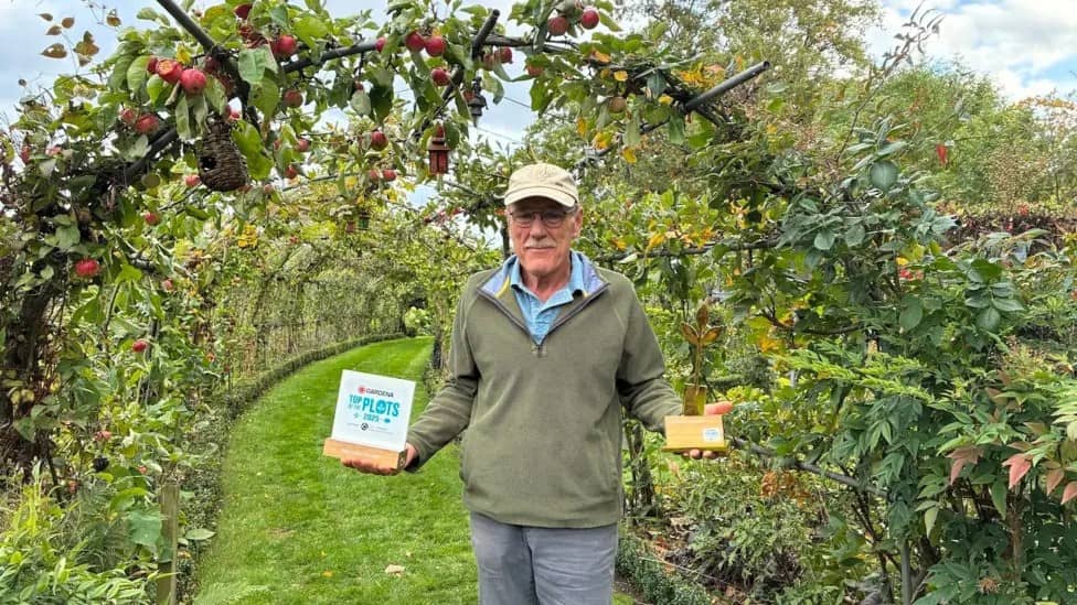 man in apple orchard holding awards
