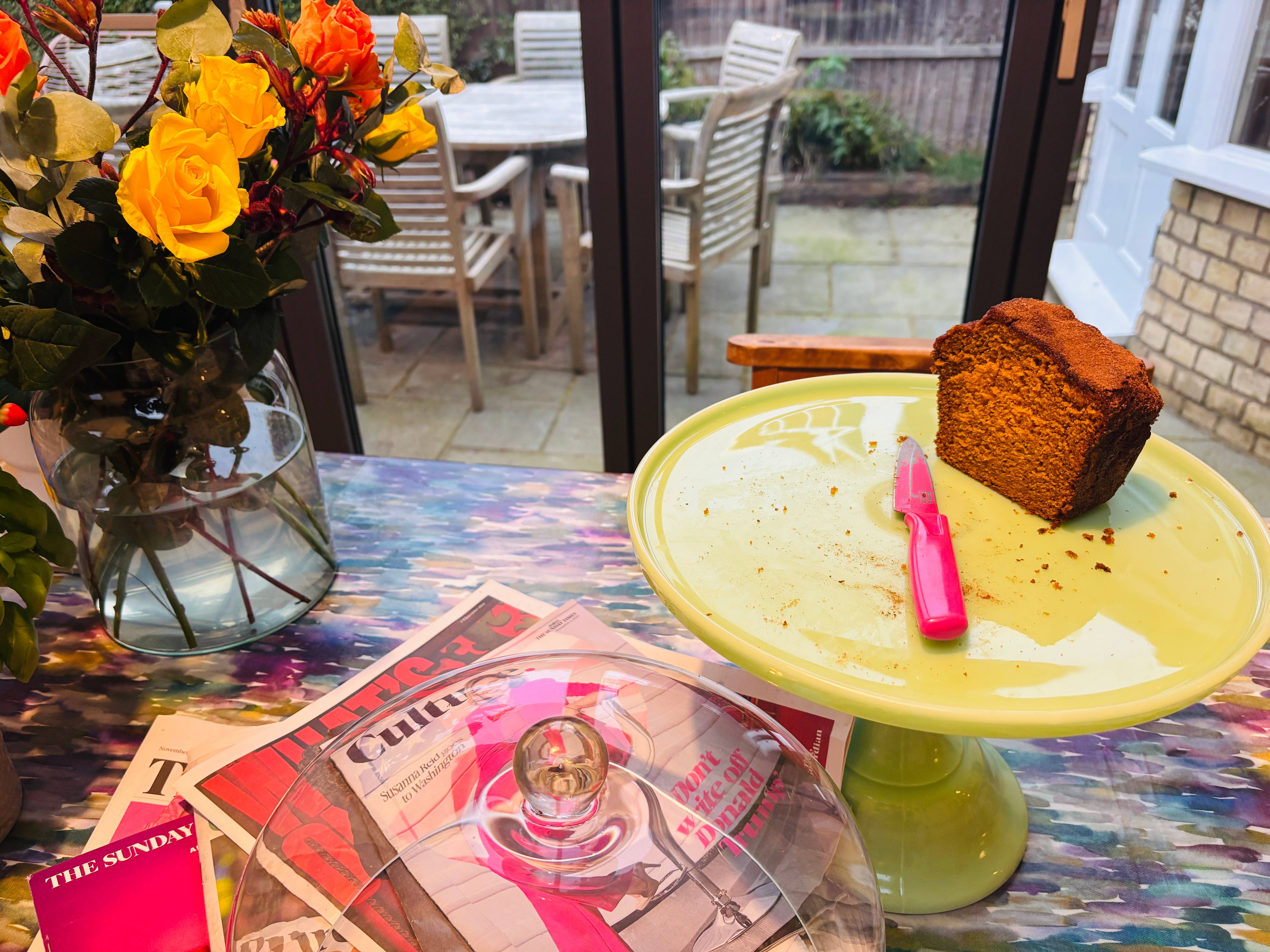 remains of pumpkin loaf cake on a cake plate and autumnal flowers in background