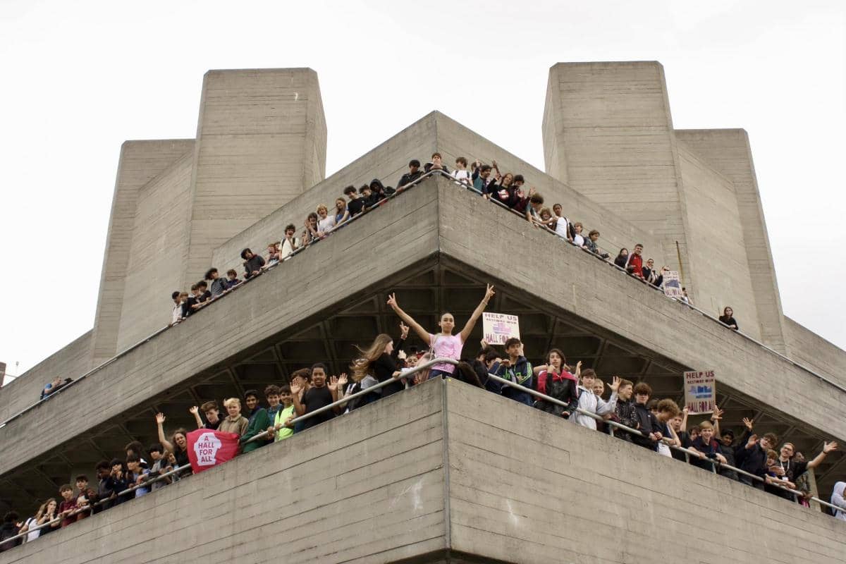 many school students standing on angluar concrete building balcony