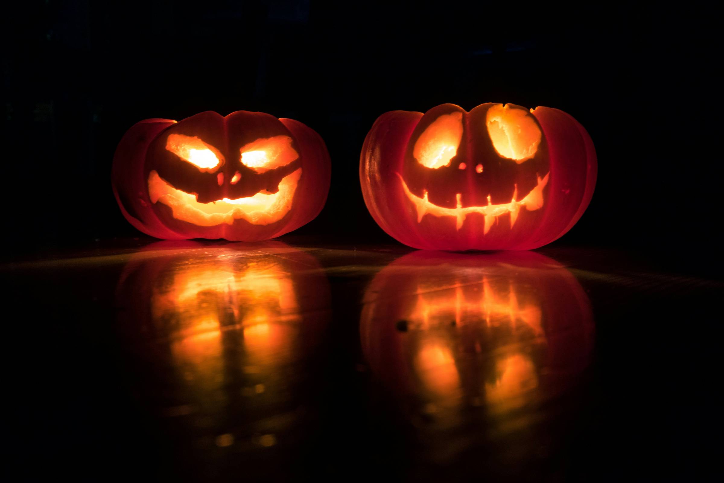two carved pumpkins lit up from the inside