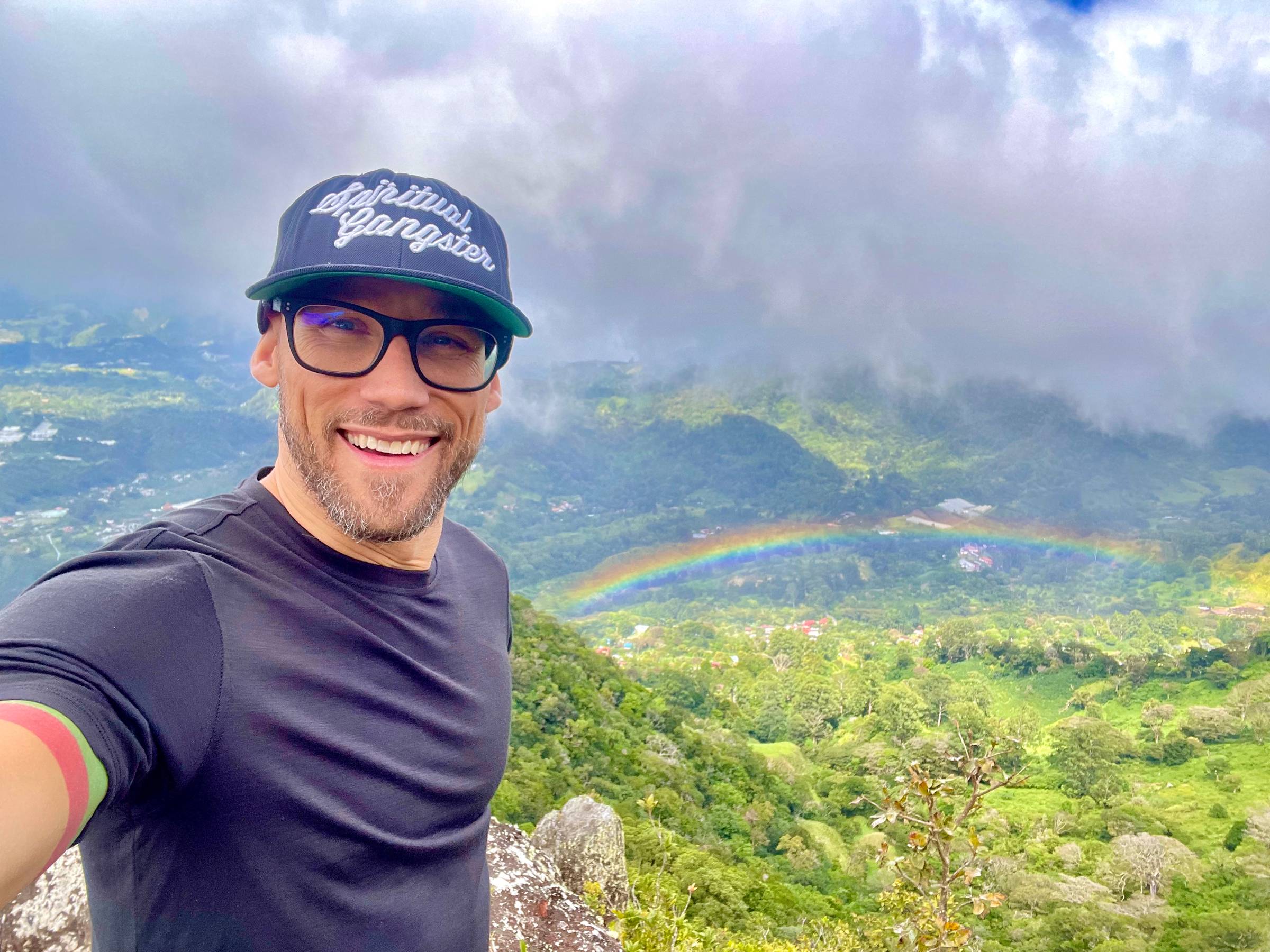 Selfie on a mountain overlooking a rainbow