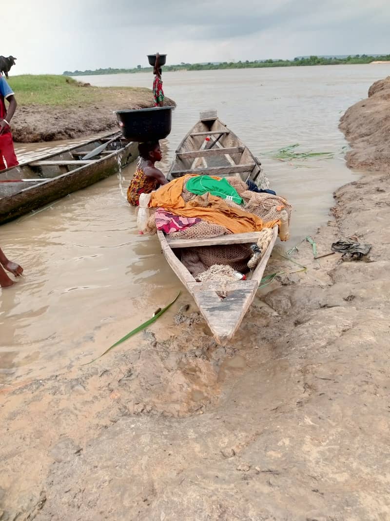 A group of people standing around a boat in the water
