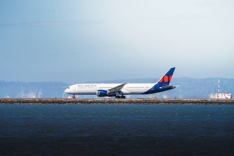 A white airplane on a runway near the ocean.