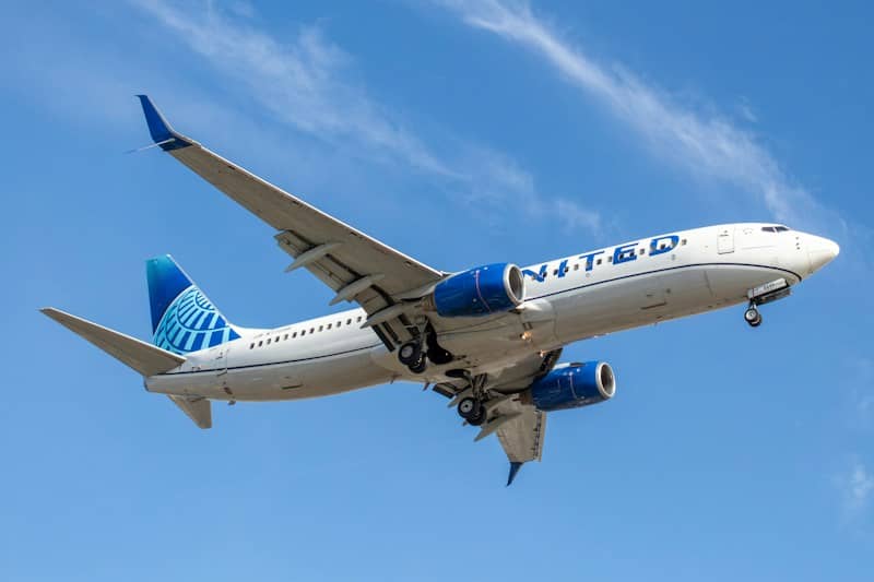 A United Airlines passenger jet flying through a clear blue sky
