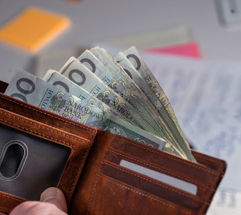 Brown leather wallet stuffed with polish currency.