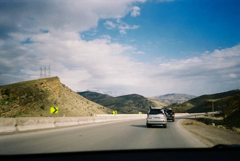 Cars driving on a highway through a mountainous landscape.