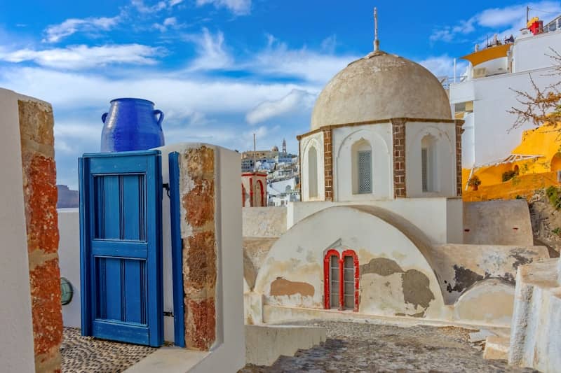 Santorini village scene with blue gate and white church dome.