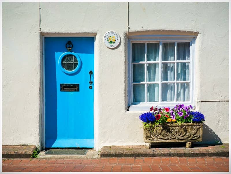 A bright blue door and window with flowers.