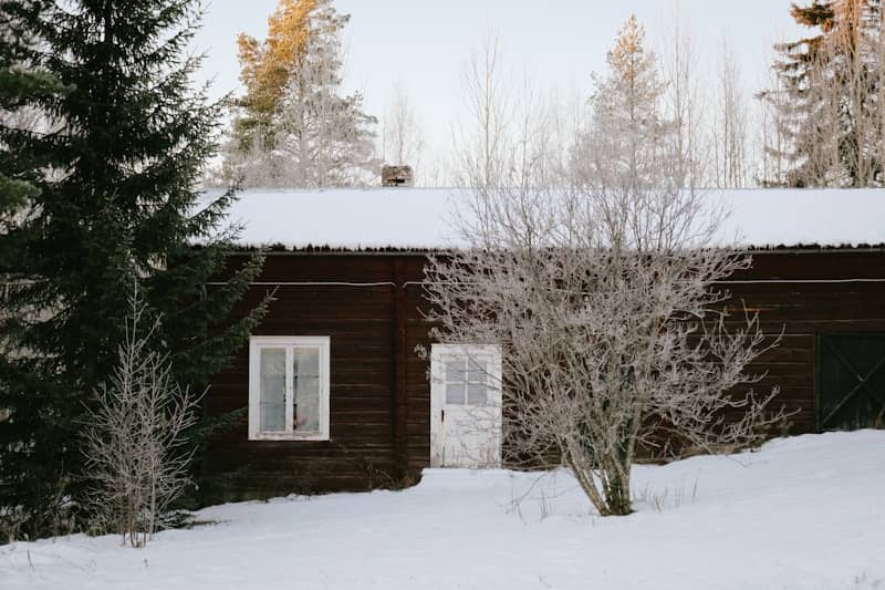 A cabin in the woods covered in snow