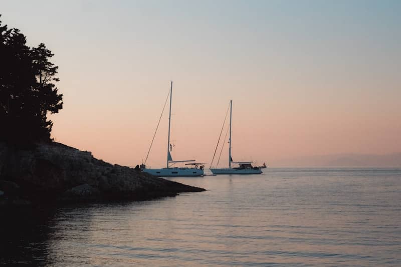 Two sailboats are peacefully anchored at dusk.