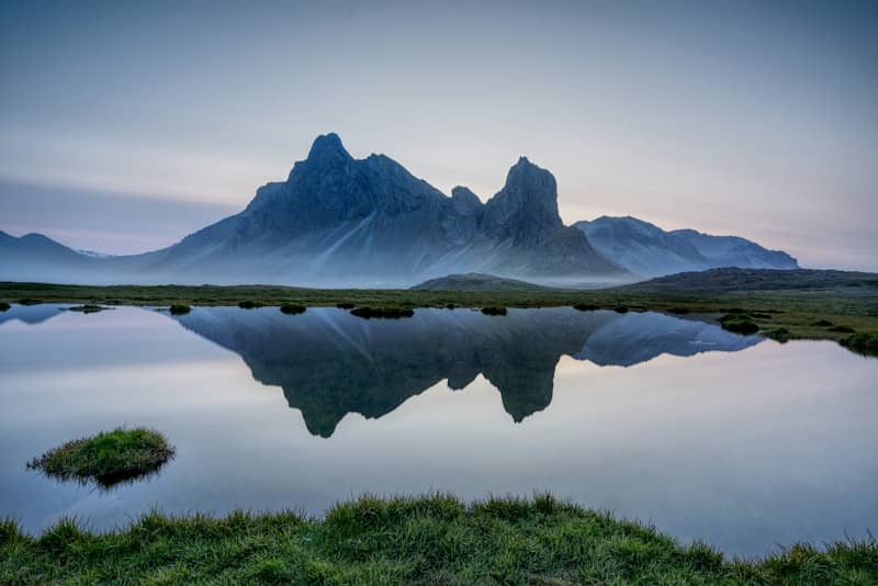 Mountains reflect in a still, blue lake.