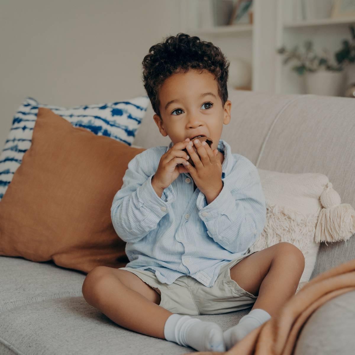 Young boy on couch eating food.