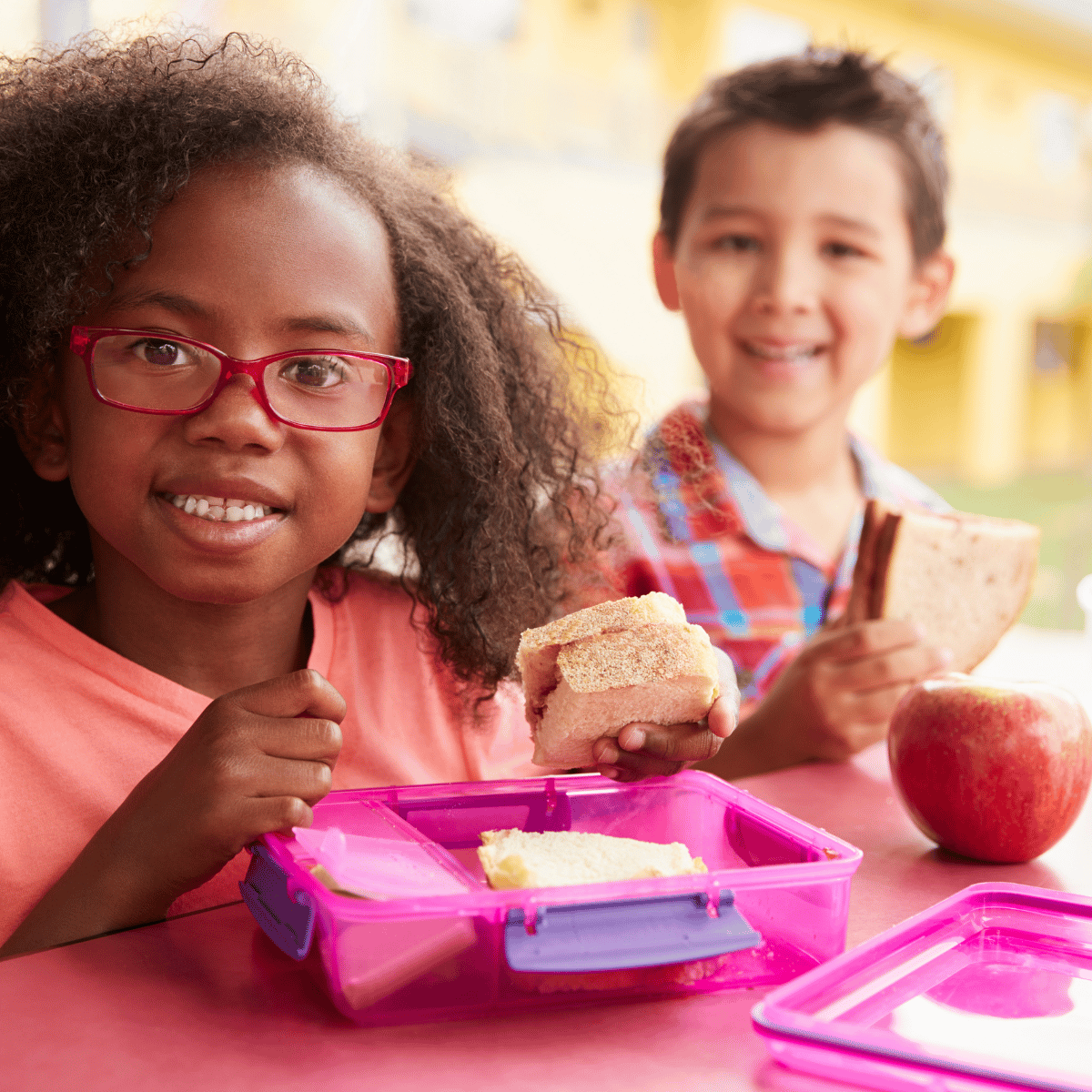 Two Children Eating Packed Lunches at Table