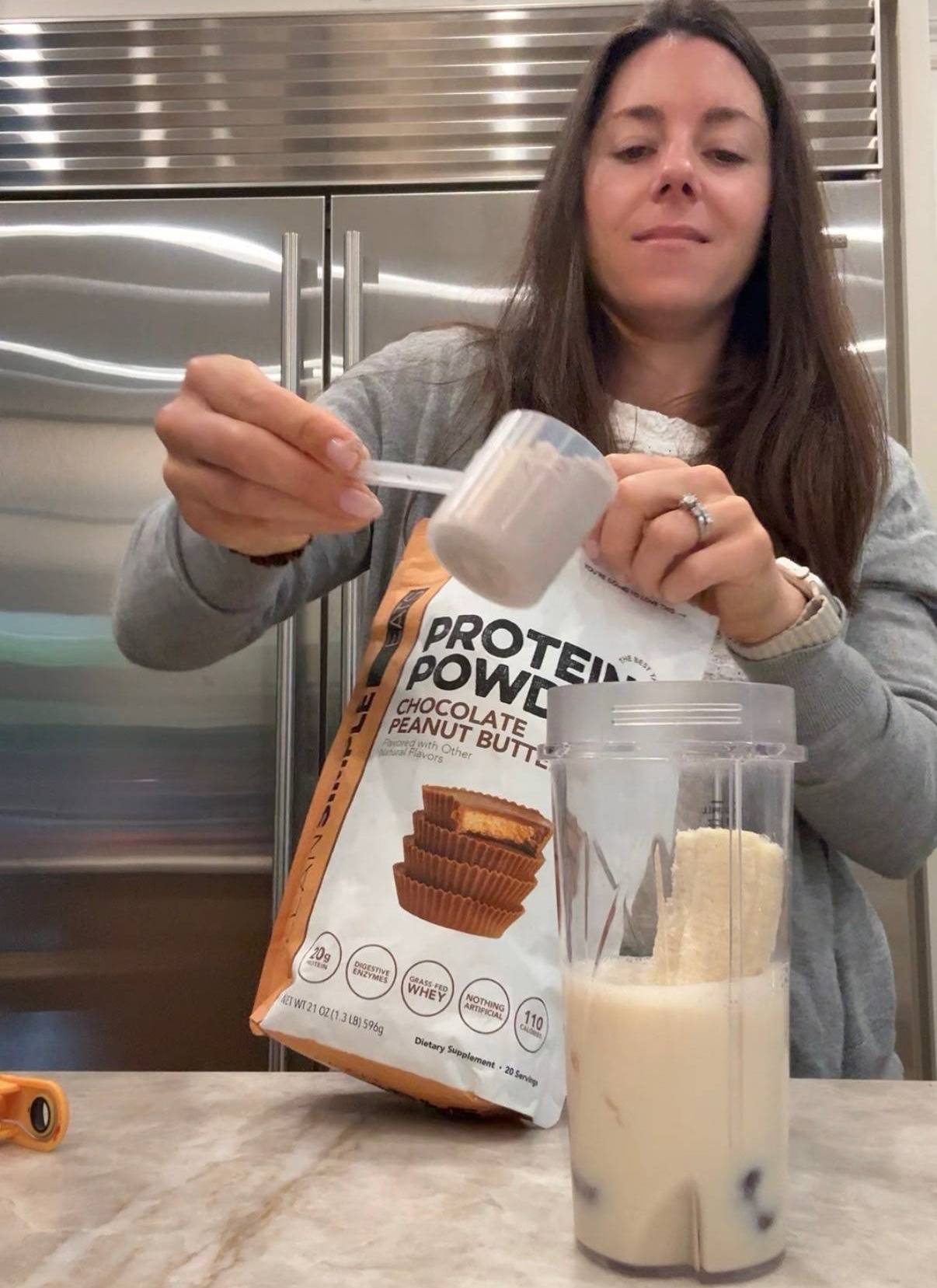 Kacie Scooping Clean Simple Eats Chocolate Peanut Butter Protein Powder into a Smoothie