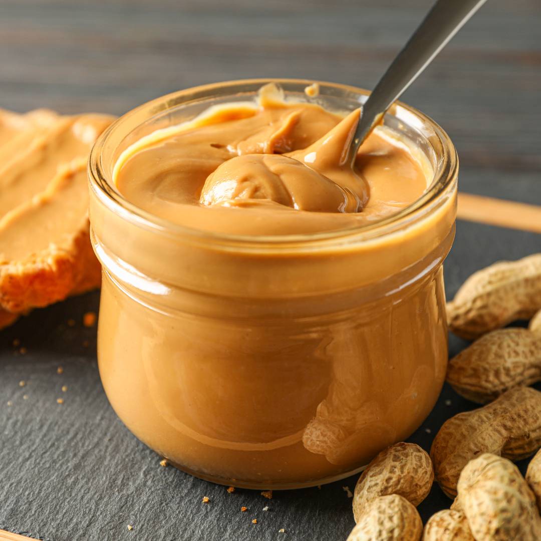 Clear Jar of Peanut Butter with a Spoon With Peanuts