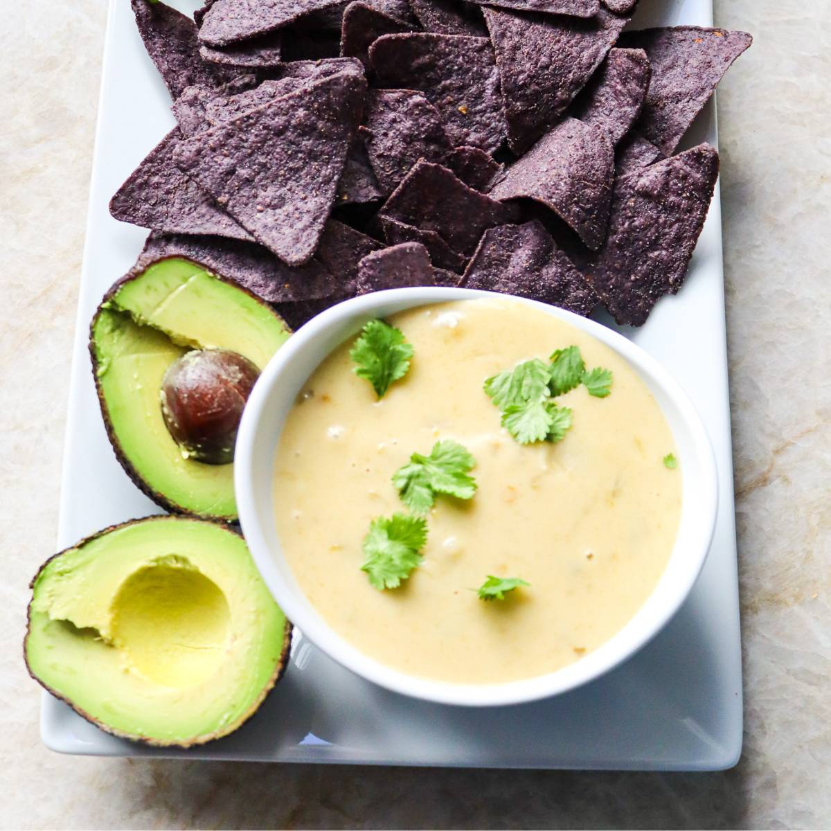 Homemade Queso on a Plate with Halved Avocado and Tortilla Chips