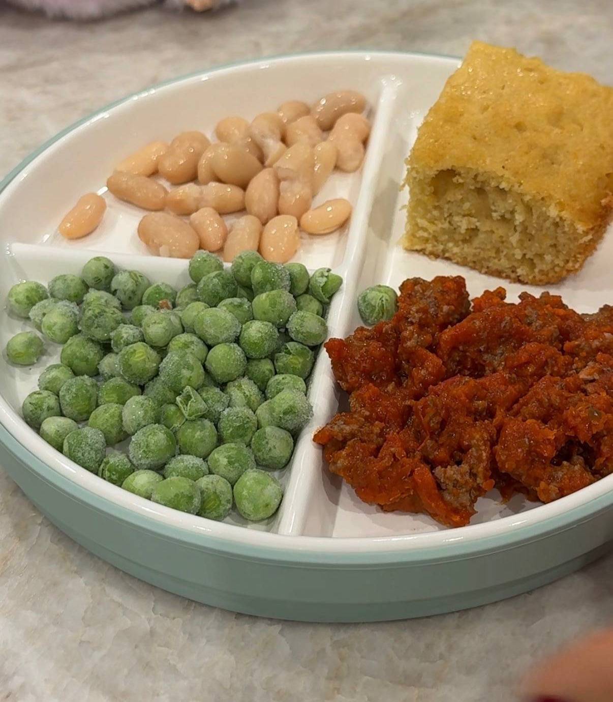 Dinner plate with meatballs, peas, white beans and bread.