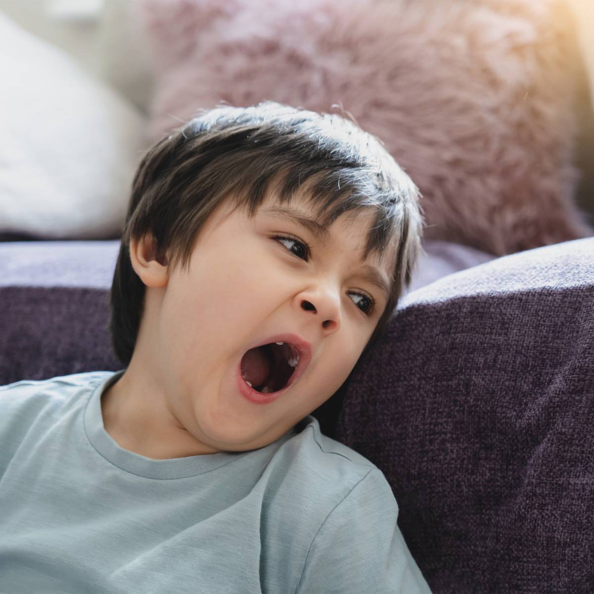 Young Boy Leaning on Couch While Yawning