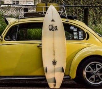 surfboard leaning on yellow car