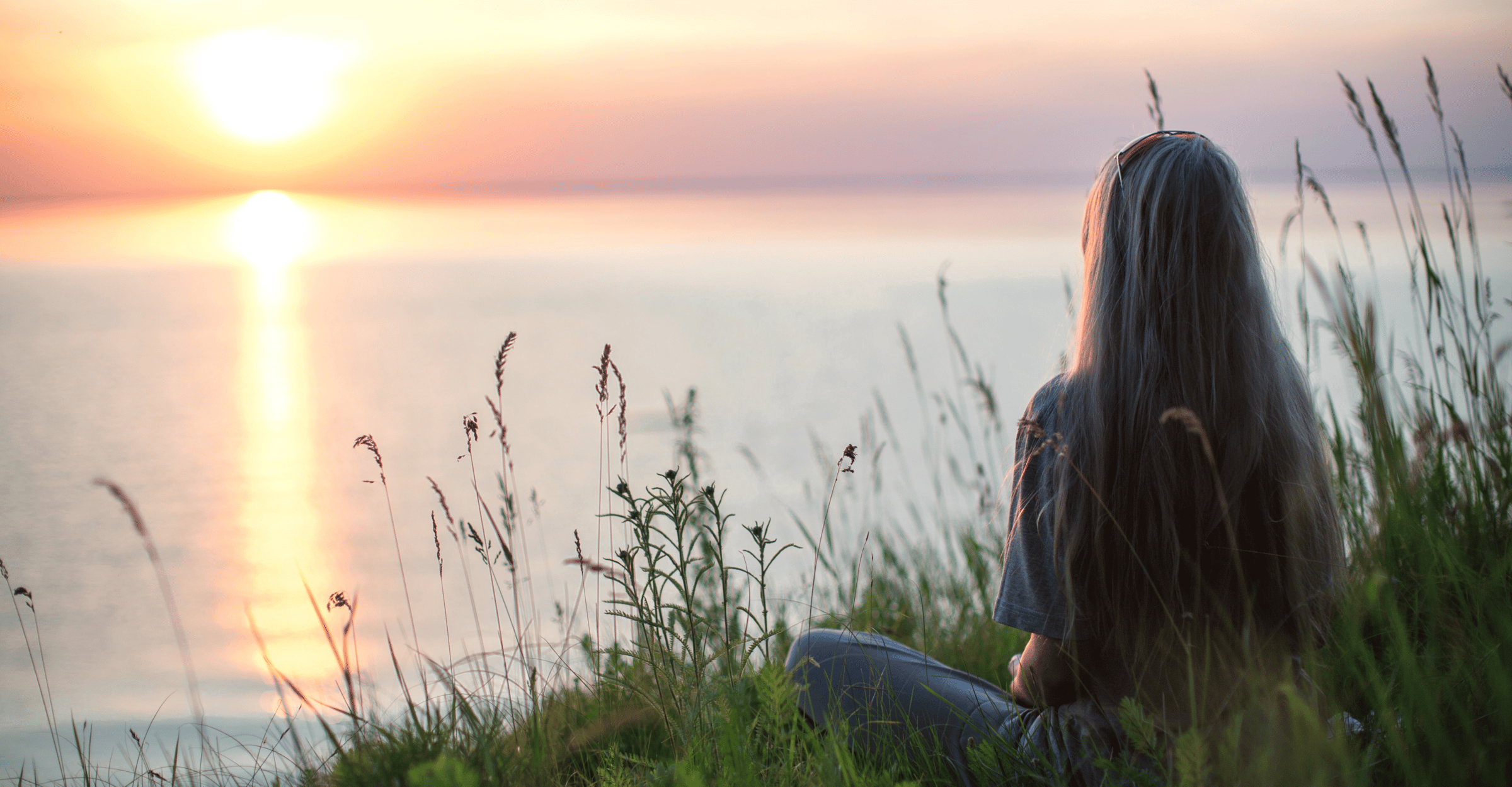 A woman gazing out over a sunset on a lake dreaming about the four foundational pillars of her online business success. 