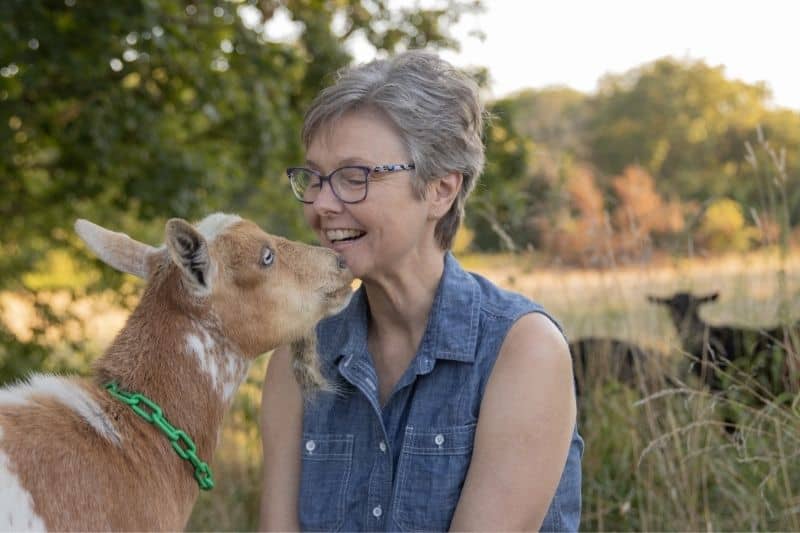 Deborah Niemann smiling with one of her goats on her farm.