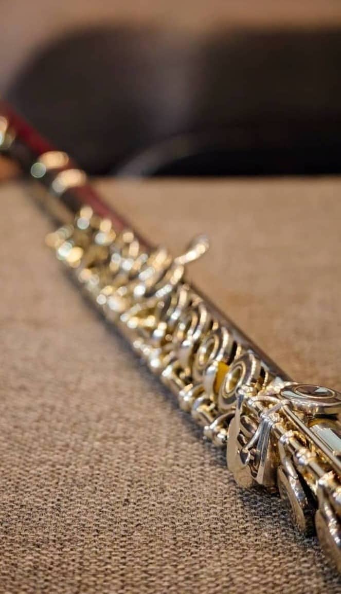 Close-up of a silver clarinet on a textured surface