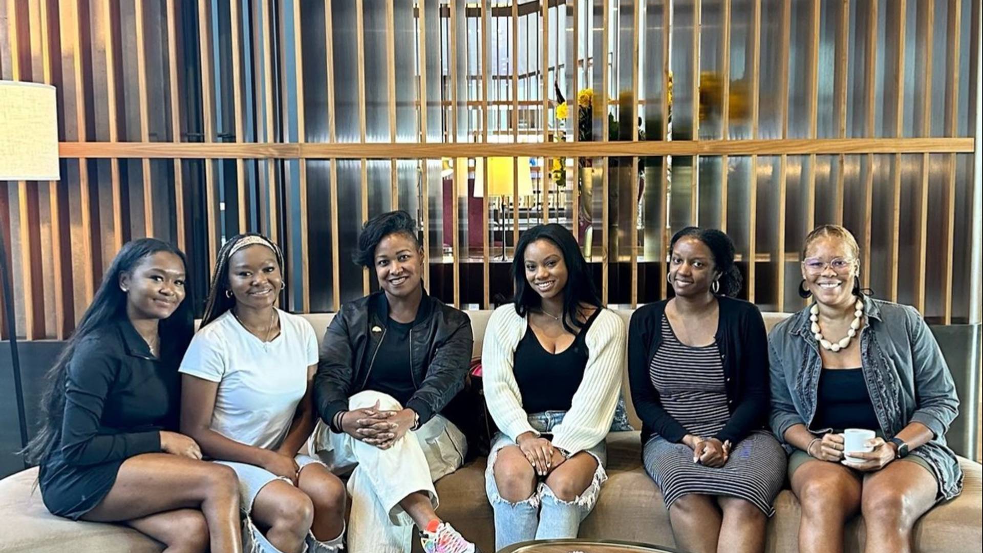 A group of 6 women wearing various clothing gathered on a couch post retreat.  