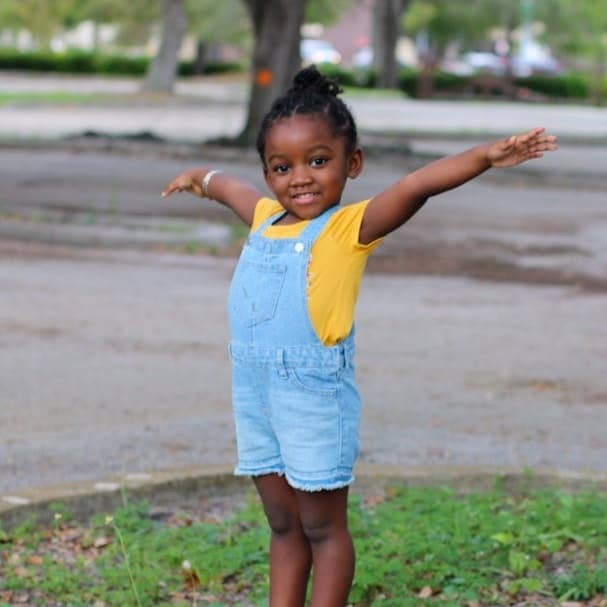 girl in yellow shirt standing on gray concrete blocks during daytime