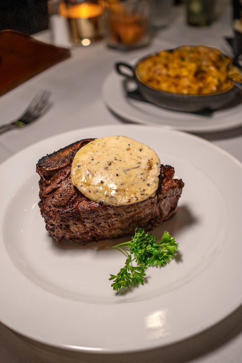 A white plate topped with a piece of steak covered in sauce