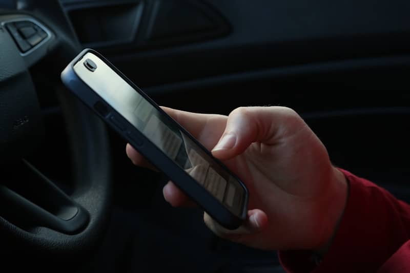 Hand holding a smartphone inside a car.
