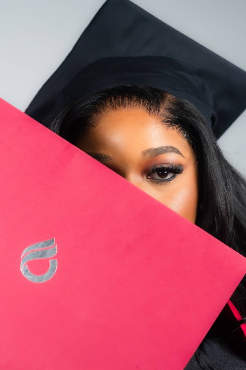 Graduating student holding a pink diploma cover.