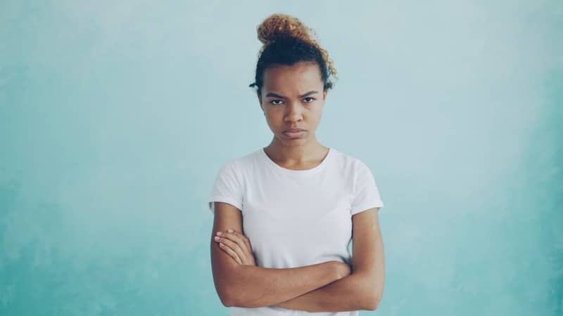 A young woman with arms crossed looking annoyed.
