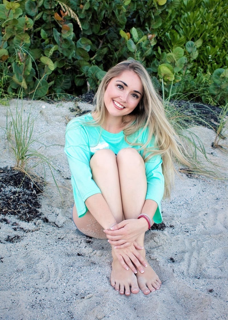 smiling girl sitting on sand during daytime