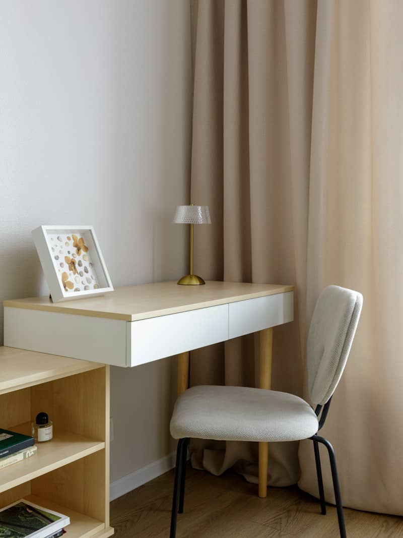 Modern workspace with a desk, lamp, and beige curtains