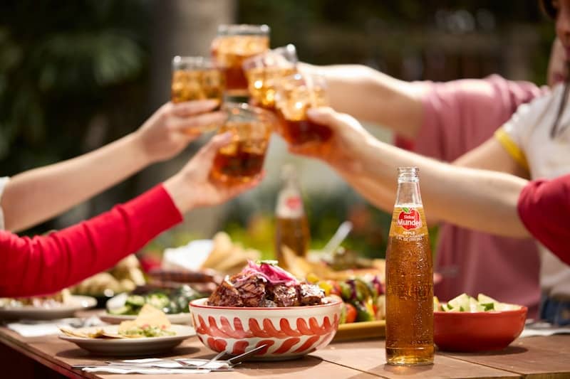 People toast with drinks at an outdoor meal.