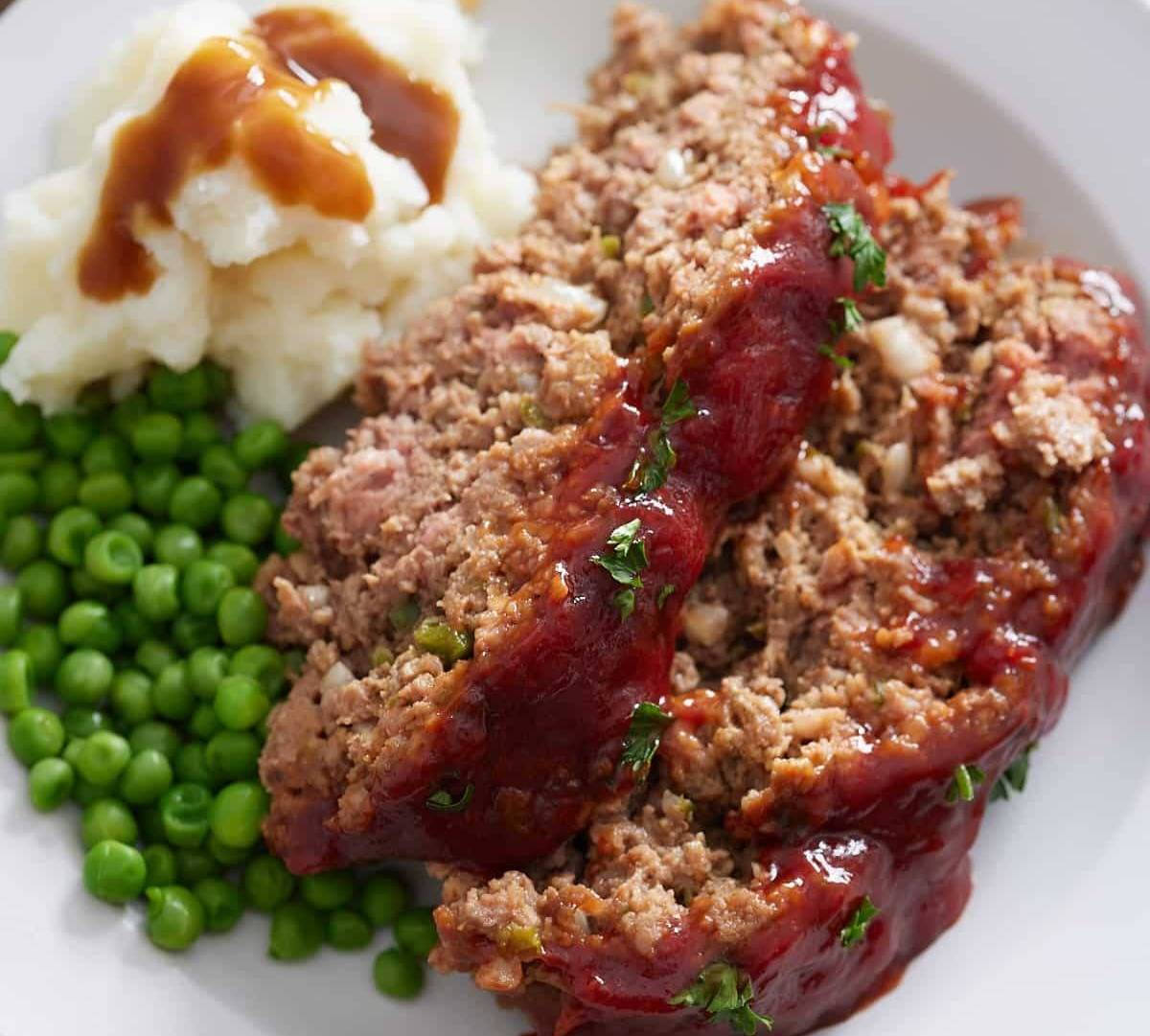 meatloaf on plate with mashed potatoes and peas
