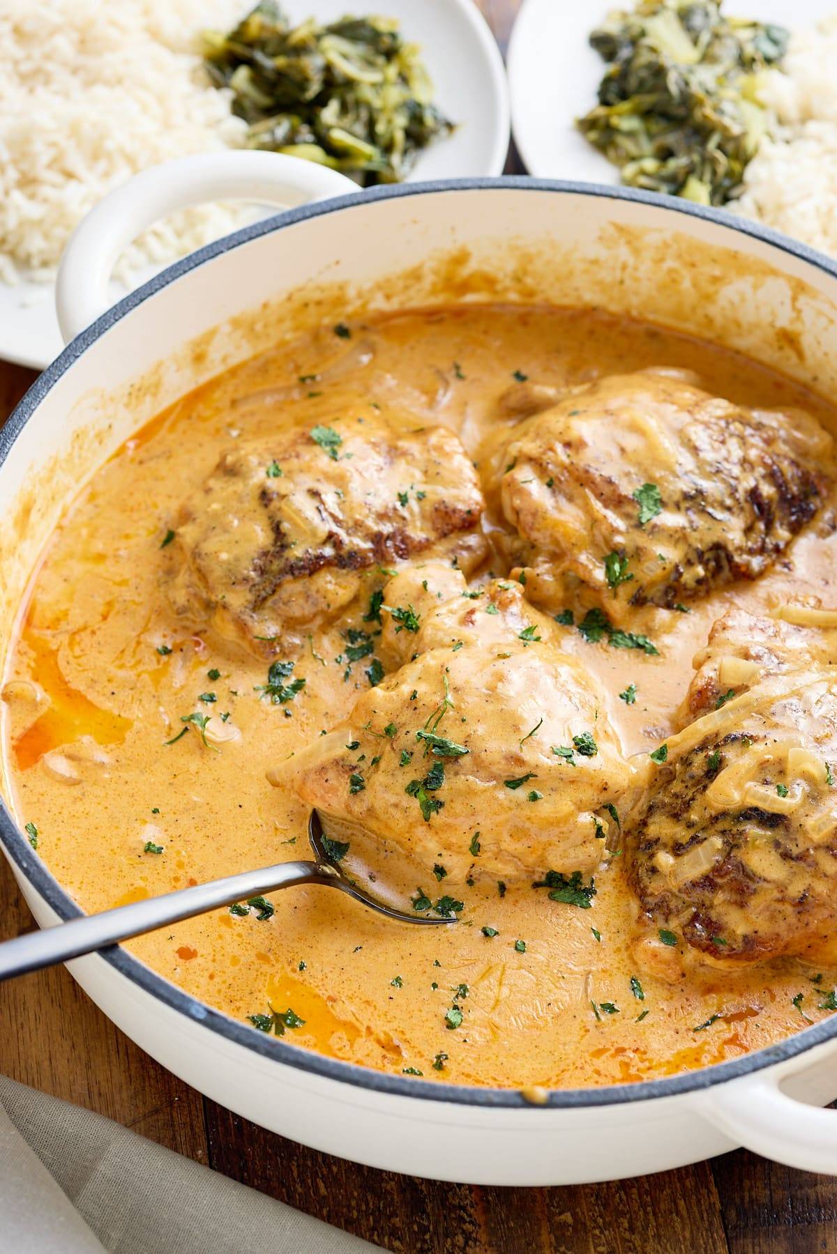 smothered chicken in a pan with spoon picking up chicken