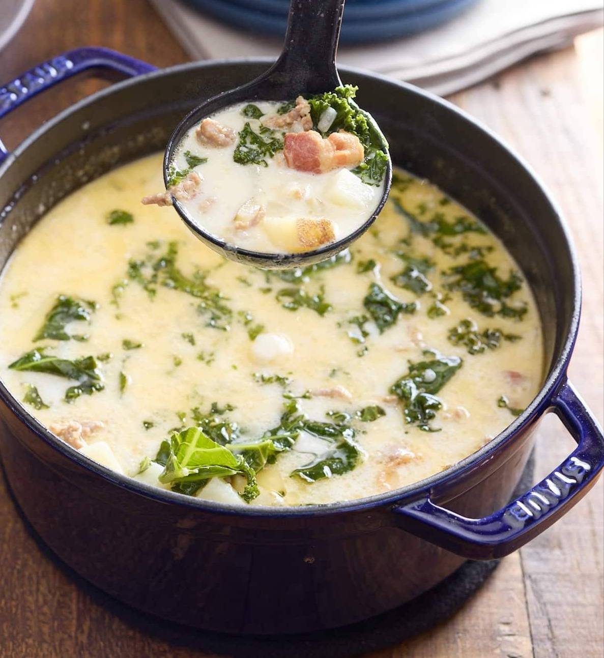 zuppa toscana in dutch oven with spoon picking it up