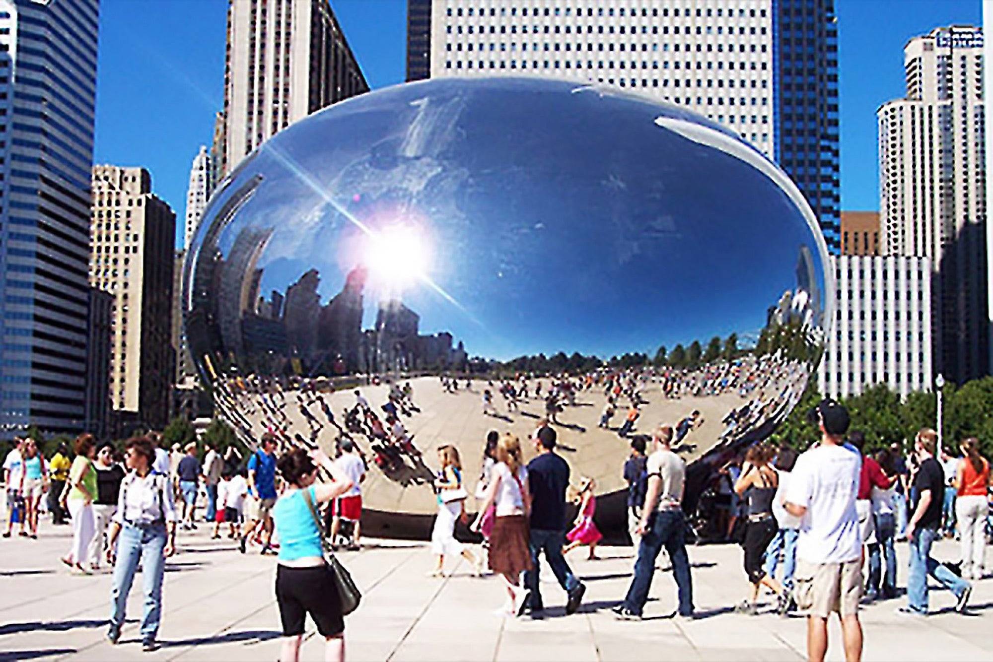 A crowded public space in front of a large, as big as a building big, shiny object