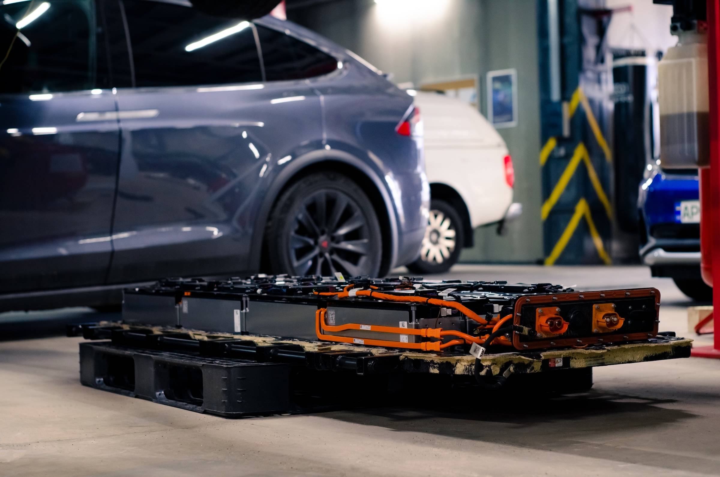Technician preparing Tesla battery replacement with EV battery pack removed during electric vehicle maintenance planning