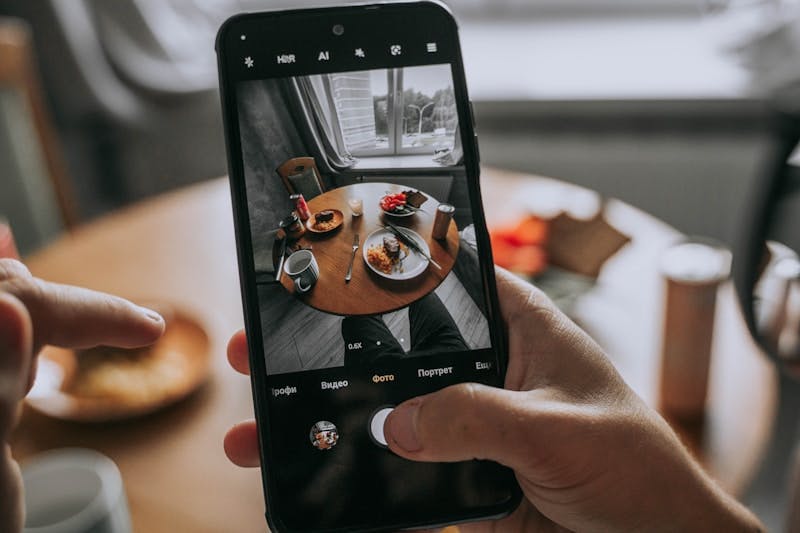 A person taking a picture of a table with food